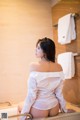 A woman in a white shirt sitting in a bathtub.