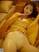 A woman in a yellow outfit laying on a bed.