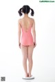 A little girl in a pink leotard standing on a scale.