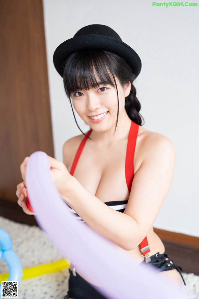 A woman in a black hat holding a purple balloon.