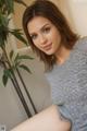 A woman sitting on a couch next to a plant.