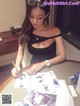 A woman sitting at a table writing on a piece of paper.