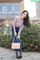 A woman in a pink top and blue jeans posing for a picture.