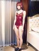 A woman in a red lingerie standing in front of a bed.