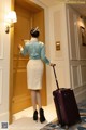 A woman standing in front of a door with a suitcase.