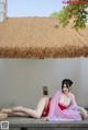 A woman in a pink kimono sitting on a wooden bench.