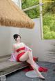 A woman in a red dress sitting on a wooden bench.