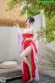 A woman in a red and pink kimono posing for a picture.