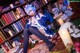 A woman sitting on the floor in front of a bookshelf.