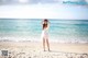 A woman standing on a beach next to the ocean.