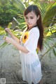 A woman in a white dress holding a sunflower.