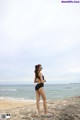 A woman in a black bathing suit standing on a beach.