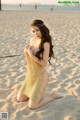 A woman in a gold dress sitting on the beach.