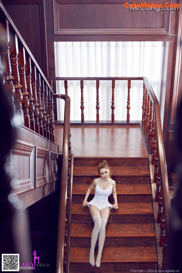 A woman in a white bodysuit sitting on a wooden staircase.
