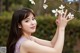 A woman in a purple dress holding a white flower.