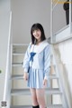 A woman in a blue and white school uniform posing for a picture.