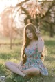 A woman sitting on the grass making a peace sign.