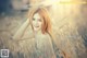 A woman in a field of tall grass posing for a picture.