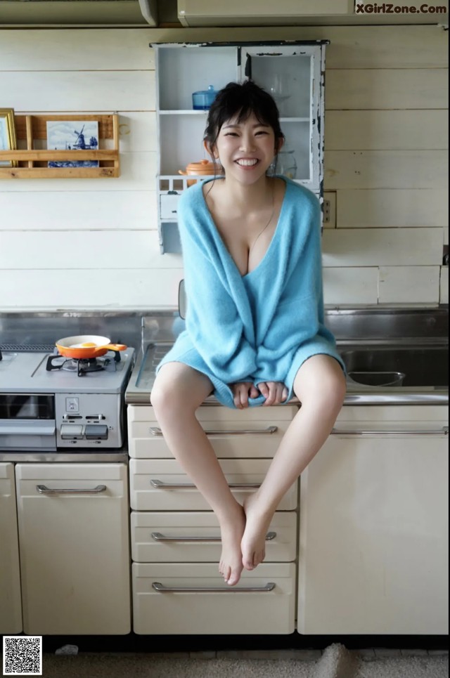 A woman sitting on top of a kitchen counter.