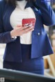 A woman in a blue suit holding a red phone case.