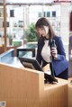 A woman in a business suit talking on a phone at a reception desk.