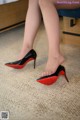 A woman wearing black and red high heels on a carpeted floor.