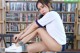 A woman sitting on top of a table next to a book shelf.