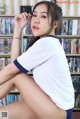 A woman sitting on a table in front of a bookshelf.