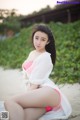 A woman in a pink bikini sitting on a beach.