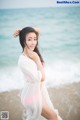 A woman standing on a beach next to the ocean.